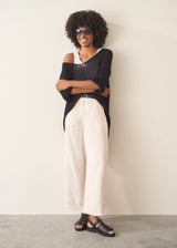 Woman wearing oversized black sweater with off white jeans and black sandals.