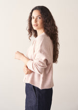 Woman wearing light blush pink button up cardigan with blue jeans