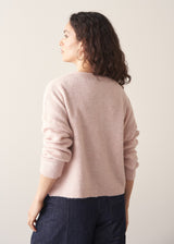 Woman wearing light blush pink button up cardigan with blue jeans