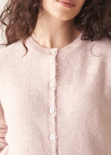 Woman wearing light blush pink button up cardigan with blue jeans