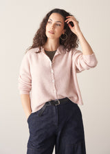 Woman wearing light blush pink button up cardigan with blue jeans