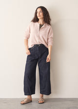 Woman wearing light blush pink button up cardigan with blue jeans