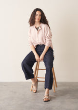 Woman wearing light blush pink button up cardigan with blue jeans