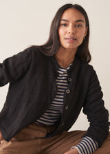Woman wearing black boxy linen jacket with metal buttons