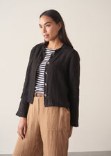 Woman wearing black boxy linen jacket with metal buttons