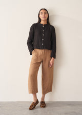 Woman wearing black boxy linen jacket with metal buttons