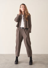 A woman wearing a dark brown check cropped jacket with matching barrel leg trousers and a white t-shirt