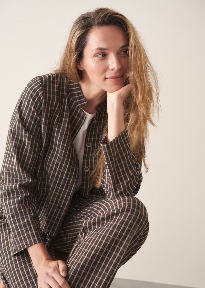 A woman wearing a dark brown check cropped jacket with matching barrel leg trousers and a white t-shirt