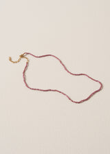 Pink beaded crystal necklace with gold chain, on a beige background
