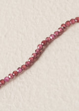 Close up of pink beaded crystals on necklace, on a beige background