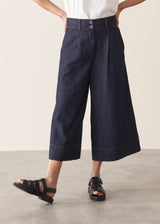 Woman wearing a white top and dark navy wide-leg denim cullottes