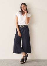 Woman wearing a white top and dark navy wide-leg denim cullottes