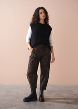 Woman wearing a white t-shirt and leopard print barrel leg trousers against a beige background