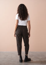 Woman wearing a white t-shirt and leopard print barrel leg trousers against a beige background