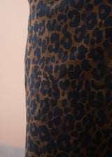 Close up of leopard print trousers worn by a model, against a beige background
