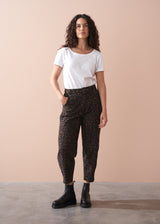 Woman wearing a white t-shirt and leopard print barrel leg trousers against a beige background