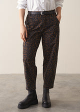 Woman wearing a white shirt and leopard print barrel leg jeans against a plain background