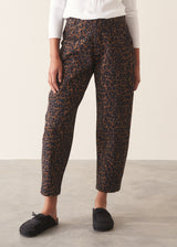 Woman wearing dark brown leopard print barrel leg trousers and a long sleeve white top