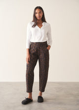 Woman wearing dark brown leopard print barrel leg trousers and a long sleeve white top