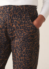 Woman wearing dark brown leopard print barrel leg trousers and a long sleeve white top