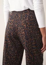 Woman wearing dark brown leopard print barrel leg trousers and a long sleeve white top
