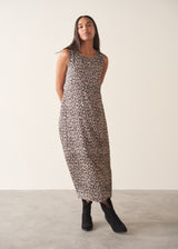 Woman wearing sleeveless satin leopard print dress with black boots and a black suede jacket