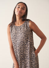 Woman wearing sleeveless satin leopard print dress with black boots and a black suede jacket