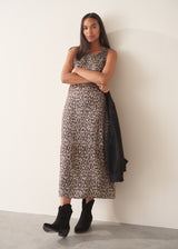 Woman wearing sleeveless satin leopard print dress with black boots and a black suede jacket