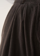 Woman wearing dark brown wide leg corduroy trousers and light checked shirt