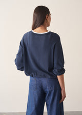 Woman wearing navy blue sweatshirt with drawstring and blue jeans