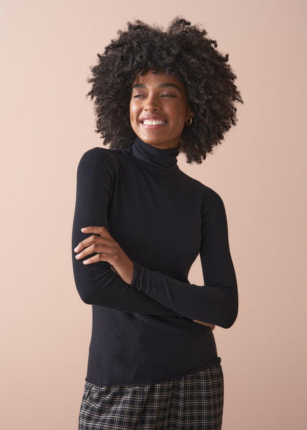 Woman wearing a black turtleneck sweater against a beige background