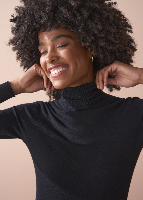 Woman wearing a black turtleneck sweater against a beige background