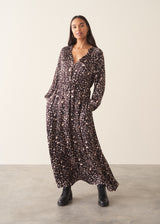 A woman wearing a brown polka dot doe print midi dress with long sleeves.