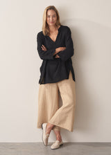 Model wearing black tunic and cropped wide leg linen trousers