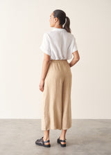 Woman wearing white linen shirt, sand wide leg linen trousers and black sandals