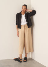 Woman wearing white linen shirt, sand wide leg linen trousers and black sandals