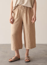 Woman wearing oatmeal sleeveless knitted top with wide leg linen trousers in oatmeal beige