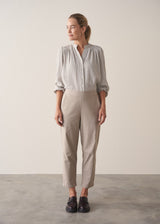 Woman wearing taupe slim fit tapered leg trousers with pale check shirt