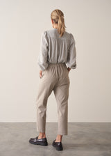 Woman wearing taupe slim fit tapered leg trousers with pale check shirt