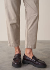 Woman wearing taupe slim fit tapered leg trousers with pale check shirt