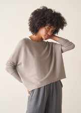 Woman wearing light grey fine knit sweater with checked linen trousers