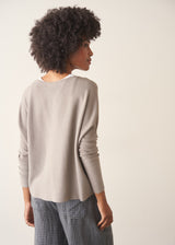 Woman wearing light grey fine knit sweater with checked linen trousers