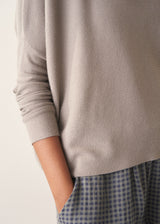 Woman wearing light grey fine knit sweater with checked linen trousers