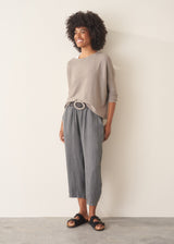 Woman wearing light grey fine knit sweater with checked linen trousers