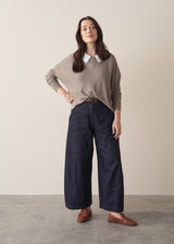 Woman wearing long sleeve stone-grey fine knit sweater with dark blue denim trousers