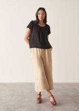 Woman wearing black linen boxy top with oatmeal linen trousers