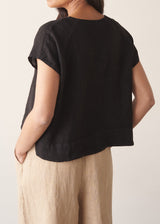 Woman wearing black linen boxy top with oatmeal linen trousers