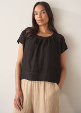 Woman wearing black linen boxy top with oatmeal linen trousers