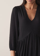 Close up of woman wearing black full length maxi dress with puffed 3/4 length sleeves