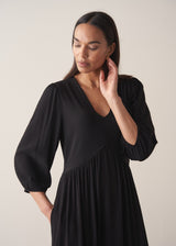 Woman wearing black full length maxi dress with puffed 3/4 length sleeves